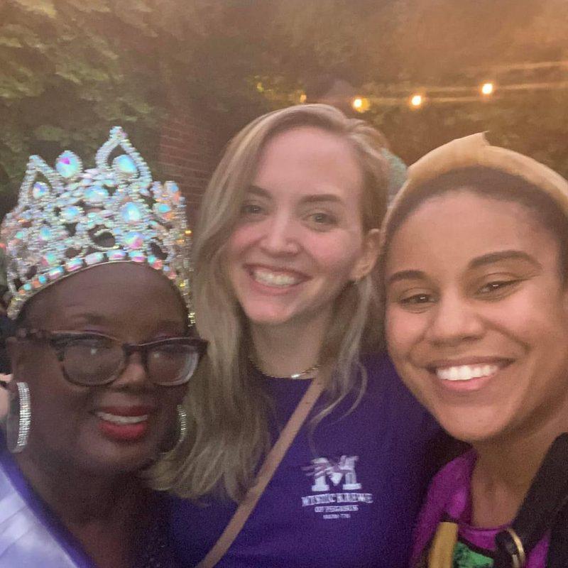 Three guests posing for a photograph, one wearing a crown