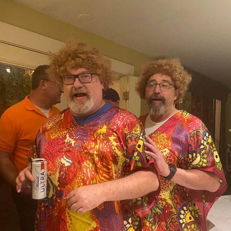 Two Krewe members in bright costume wigs and shirts