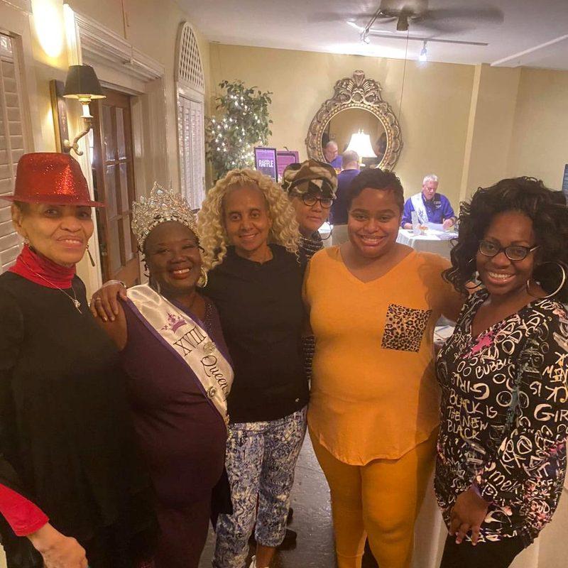 A group of Krewe members in sashes at an event
