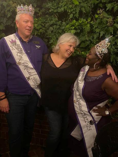 The King of the Krewe laughing with two guests in a garden.