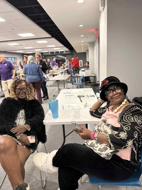 Two guests in hats seated at an auction table.