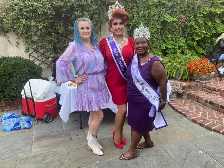 Three guests in crowns and costume in a brick courtyard.