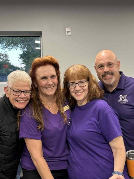 Four Krewe volunteers in purple shirts, grinning.