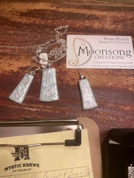 Hand-made silver pendants above a Krewe bid sheet.